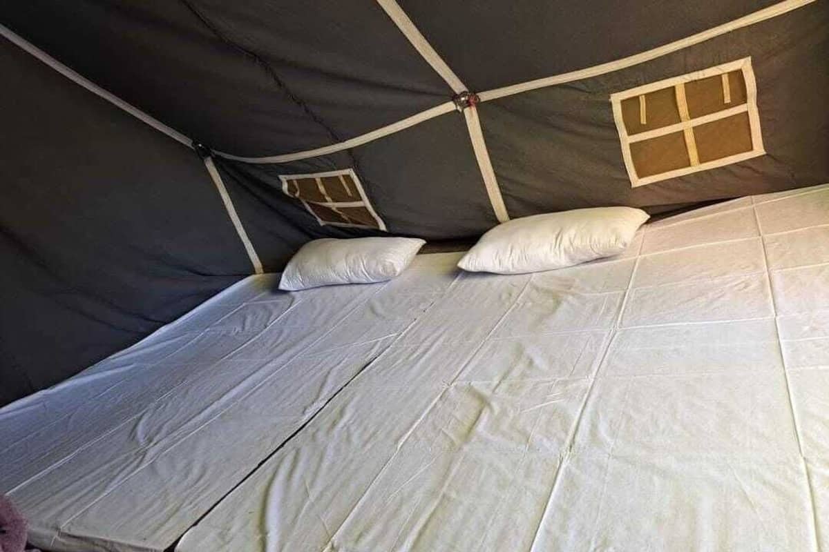 A tent with a bed, pillows, and a window.