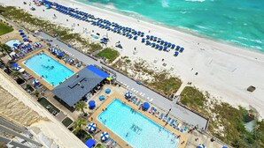 A resort with two swimming pools, beachside lounge areas, and a view of the ocean. - Fall Deals + Snowbird Rates | Gulf Front Beach Escape (Panama City Beach)