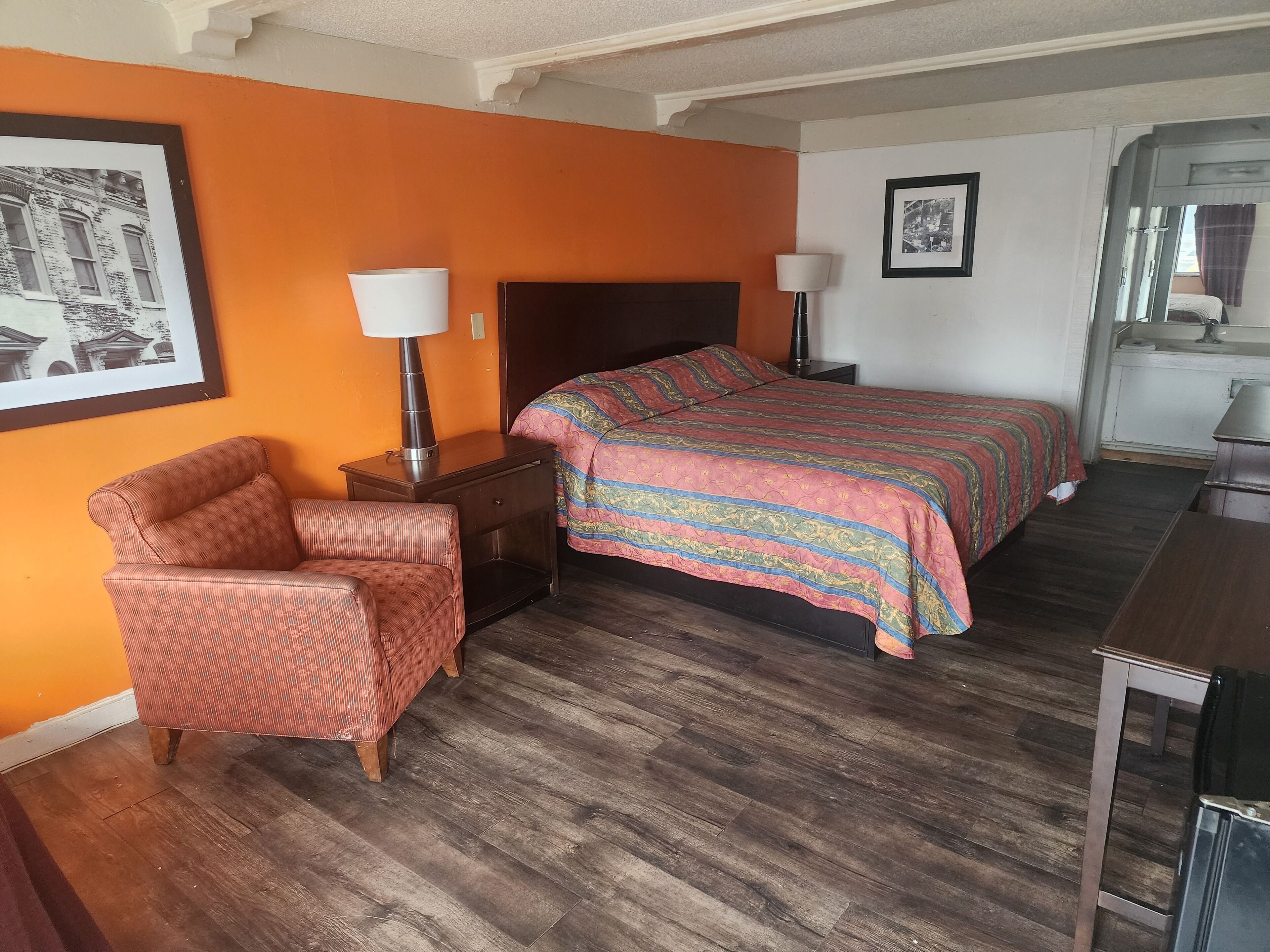 Una habitación de hotel con cama, una silla, una mesita de noche y un escritorio.