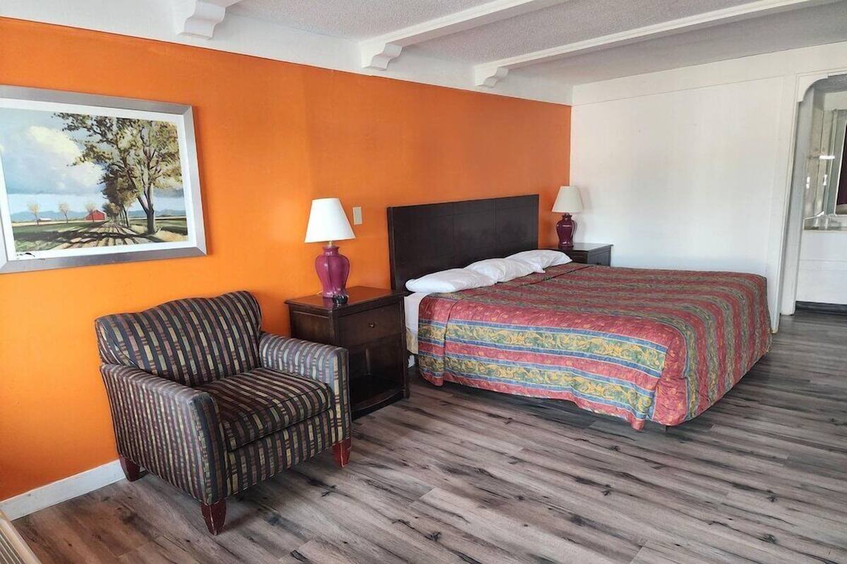 A hotel room with a bed, a chair, and a nightstand.