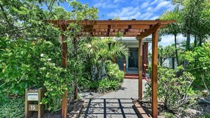A wooden pergola entrance with a pathway leading to a building, surrounded by lush greenery and a mailbox with the number 15. - Family Friendly Walk to Beach Tropical Retreat + BBQ Deck (Point Vernon)