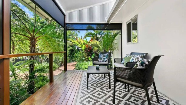 A balcony with a wooden floor, a patterned rug, and a seating area with a table and chairs. - Family Friendly Walk to Beach Tropical Retreat + BBQ Deck (Point Vernon)