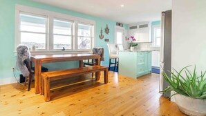 Una habitación con un banco de madera, una silla, una mesita y una planta en maceta.