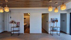 A modern interior with a wooden ceiling, pendant lights, and a hallway leading to a dining area. - COARM0106 - Edificio Art Studio (Salvador)
