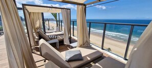 A balcony with a view of the beach and ocean.