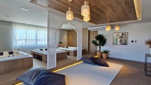 A modern spa room with a large bathtub, seating area, and wooden accents. - COARM0106 - Edificio Art Studio (Salvador)