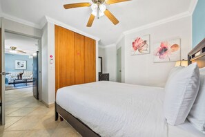 A bedroom with a bed, wooden wardrobe, ceiling fan, and artwork on the wall. - Charming 2BR Home • Outdoor Kitchen (Noord)