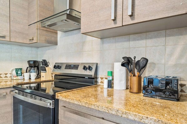 A modern kitchen with a stainless steel stove, a built-in oven, a coffee maker, and a toaster.