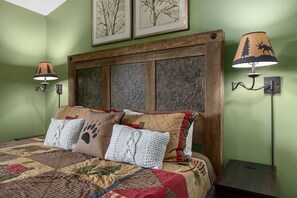 Une chambre à coucher avec une tête de lit en bois, une couvre-lit matelassée et deux lampes fixées au mur.