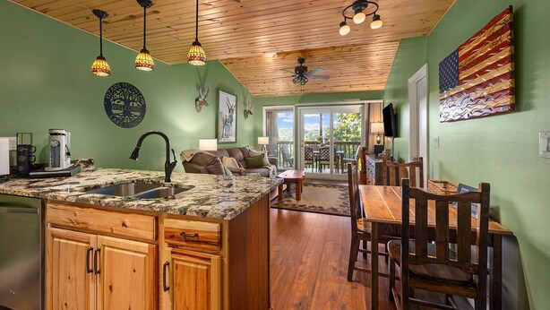 A kitchen with a large island, wooden cabinets, and pendant lighting. - Ozark Mountain Lake Home (Branson West)