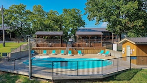 A swimming pool with lounge chairs, a wooden deck, and a fenced area. - Ozark Mountain Lake Home (Branson West)