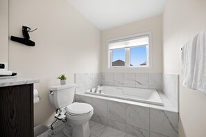 A modern bathroom with a toilet, sink, and bathtub.