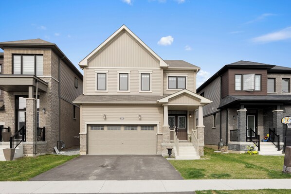 A two-story residential house with a garage, a front porch, and a small front yard.