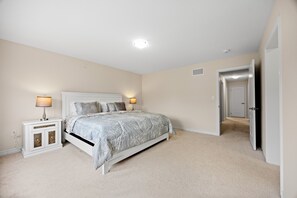 A bedroom with a bed, nightstands, and a door leading to another room.
