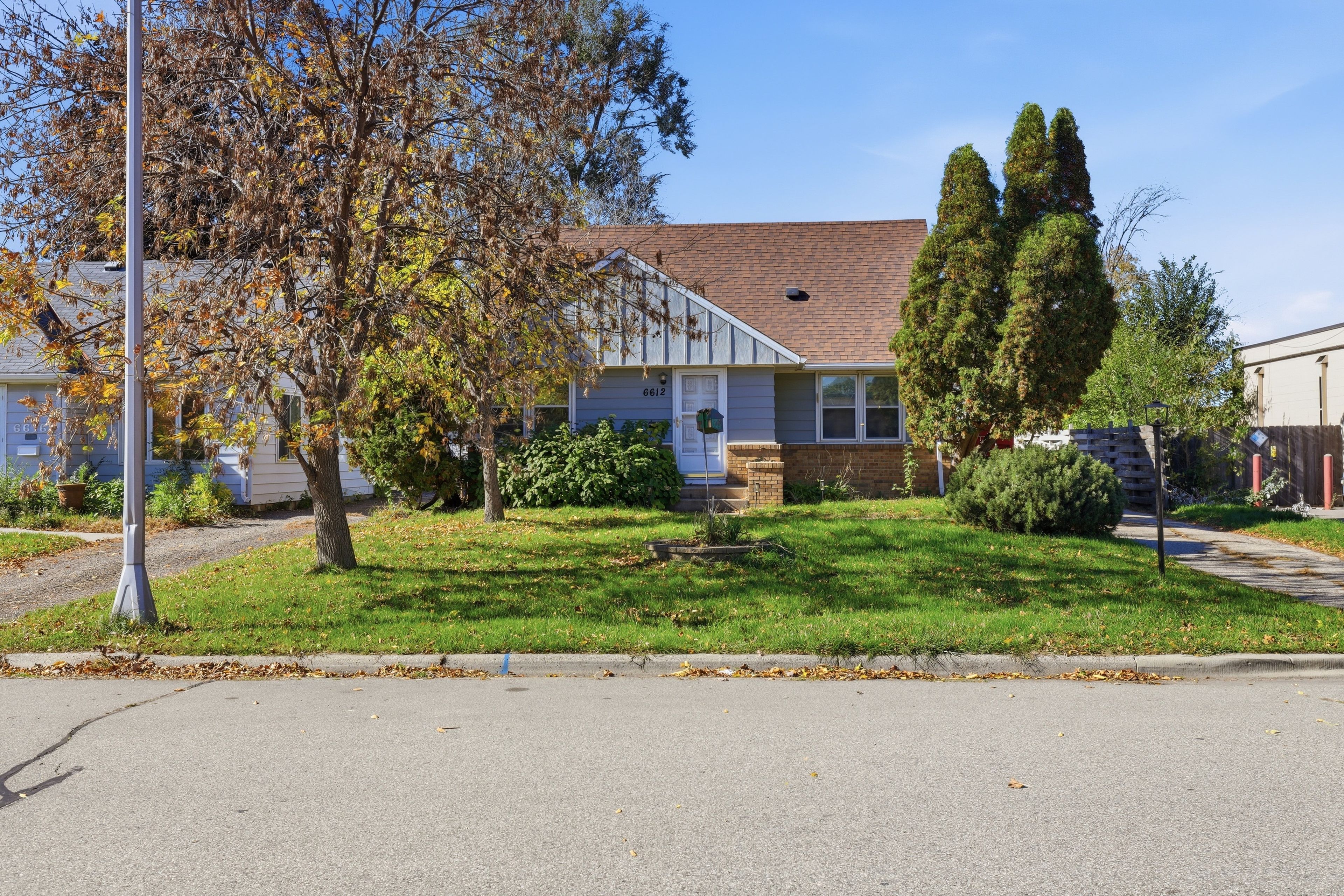A residential house with a front yard, a mailbox, and a street lamp.