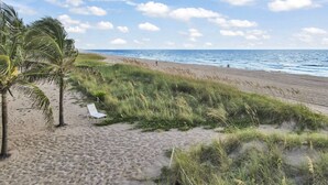 Una playa con una silla de descanso blanca y palmeras.