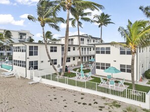 Um hotel à beira-mar com vários andares, áreas de estar ao ar livre e palmeiras.