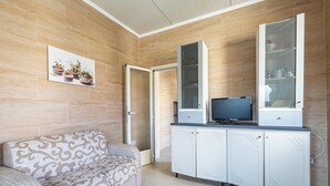 Una sala de estar moderna con un sofá estampado, un mueble con televisor y una puerta que da a otra habitación.