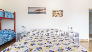Un dormitorio con cama, dos mesitas de noche, una litera roja, un cuadro de un muelle y un adorno de pared.