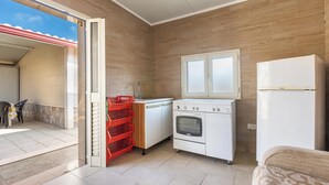 Una cocina compacta con horno integrado, refrigerador y ventana sobre el fregadero.