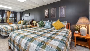 A hotel room with two beds, a dark wall, and framed pictures.