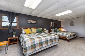 Een slaapkamer met twee bedden, een raam met gordijnen, een kleine tafel en een bord aan de muur.