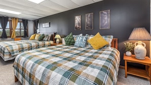 Een hotelkamer met twee bedden, een donkere muur en afbeeldingen in lijsten.