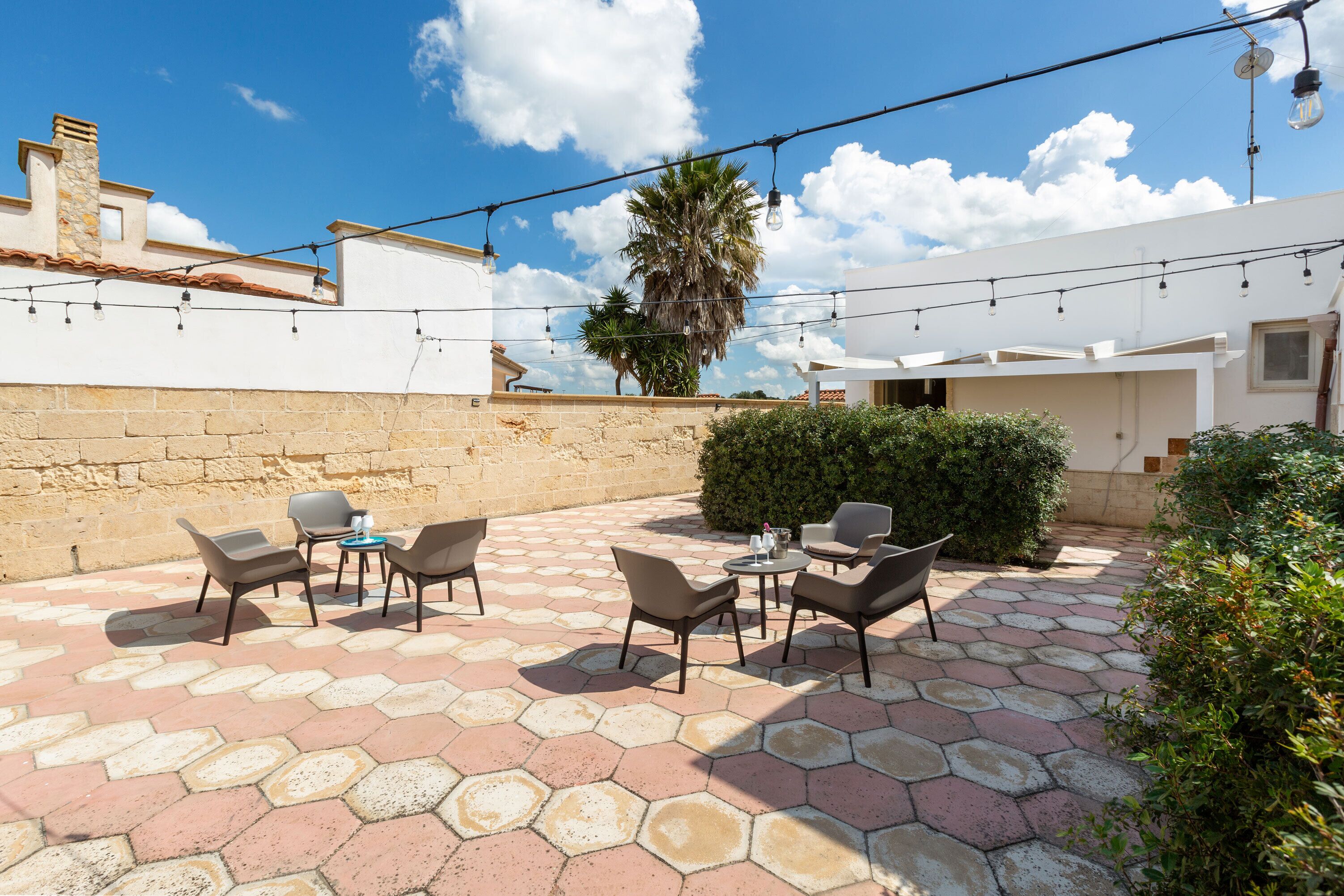 A patio with hexagonal tiles, outdoor furniture, and string lights.