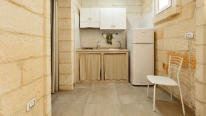 Una cocina compacta con gabinetes blancos, un lavamanos y un refrigerador blanco.