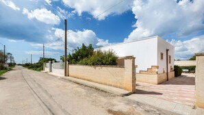 Un edificio blanco con entrada pavimentada y pared de ladrillo.