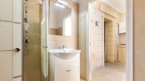 Un baño moderno con ducha de vidrio, lavamanos blanco y espejo.