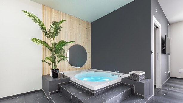 Un bagno moderno con una vasca freestanding, una grande pianta in vaso e un design minimalista.