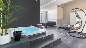 Una camera da letto moderna con un grande letto, una poltrona sospesa, una vasca da bagno e una pianta in vaso.