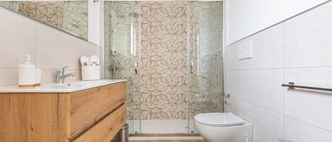 Une salle de bain moderne avec un meuble-lavabo en bois, une cabine de douche en verre, des toilettes et un lavabo.