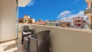 A balcony with wicker chairs, a metal pole, and a view of surrounding buildings. - Mezzaluna Luxury Rooms - Mono Home (Mesagne)
