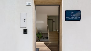 A hotel entrance with a wooden staircase, a door, and a sign for Mezzaluna Luxury Rooms. - Mezzaluna Luxury Rooms - Mono Home (Mesagne)