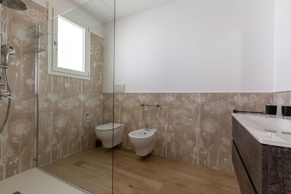 A modern bathroom with a shower, toilet, bidet, and sink.