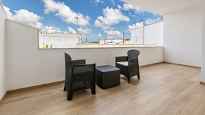 Un balcón con muebles de mimbre y vistas a la ciudad.