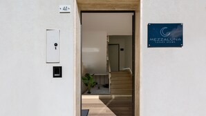 Entrada de un hotel con una escalera de madera, una puerta y un letrero que anuncia Mezzaluna Luxury Rooms.
