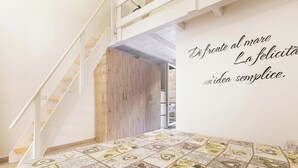 Un dormitorio con una colcha estampada, un armario de madera y una escalera blanca.