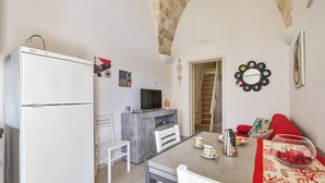 Una cocina compacta con un refrigerador blanco Bosch, una mesa de comedor con sillas y un mueble blanco pequeño.
