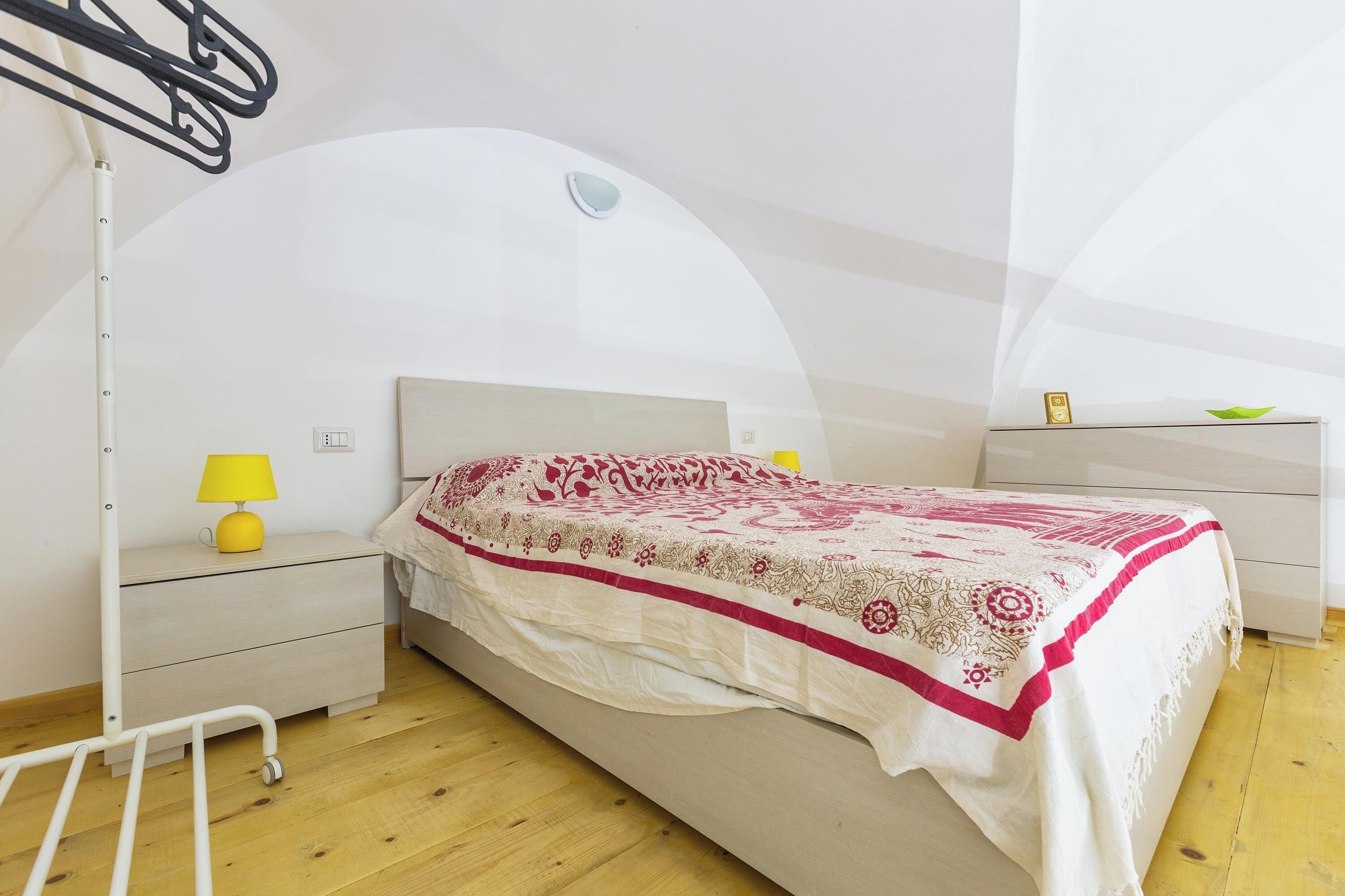 A bedroom with a bed, bedside tables, a lamp, and a nightstand.