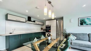 A modern kitchen with a glass dining table, green cabinets, and a grey sofa in the living area. - Whole house with parking and garden in Conwy. Pets welcome (Conwy)