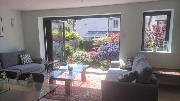 A living room with a sofa, a glass coffee table, and a view of a garden through a sliding door. - Whole house with parking and garden in Conwy. Pets welcome (Conwy)