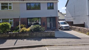 A two-story residential house with a brick facade, large windows, and a car parked in the driveway. - Whole house with parking and garden in Conwy. Pets welcome (Conwy)
