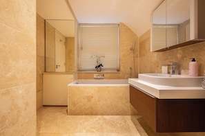 A modern bathroom with a bathtub, a sink, and a large mirror. - Paddington 7-bed 13-guest Massive House W/patio (London)