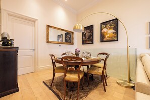 A dining area with a round table, chairs, a floor lamp, and wall-mounted artwork. - Paddington 7-bed 13-guest Massive House W/patio (London)