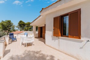 Un patio techado al aire libre con una mesa, sillas y un mantel blanco.