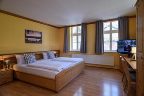 Ein Hotelzimmer mit einem großen Bett, einem Schreibtisch, einem Fernseher und einem Gemälde an der Wand.