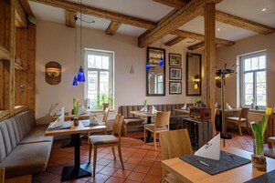 A restaurant with wooden beams, tiled floors, and a mix of seating including tables and booths.